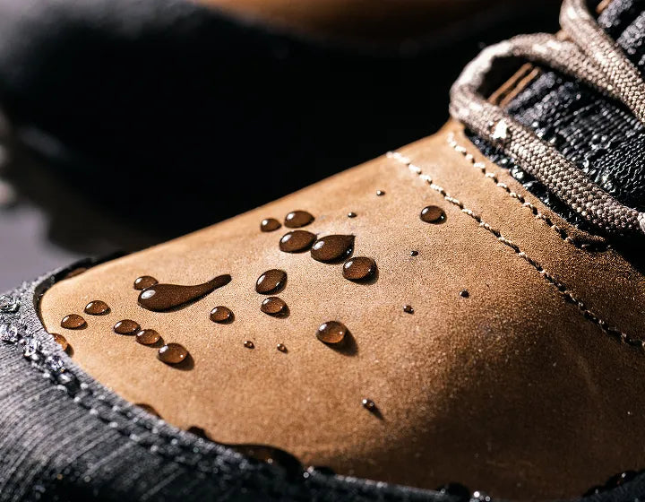 Close-up of a brown leather boot with water droplets on the sole.