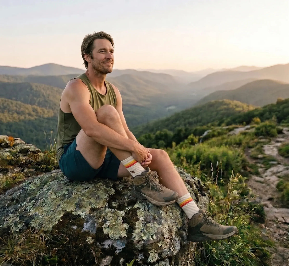 Man sitting on a rock with a scenic mountain view in the background